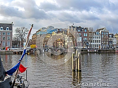 Dutch flag on the boat with bridge and Amsterdam famous duch traditional Flemish brick buildings Editorial Stock Photo